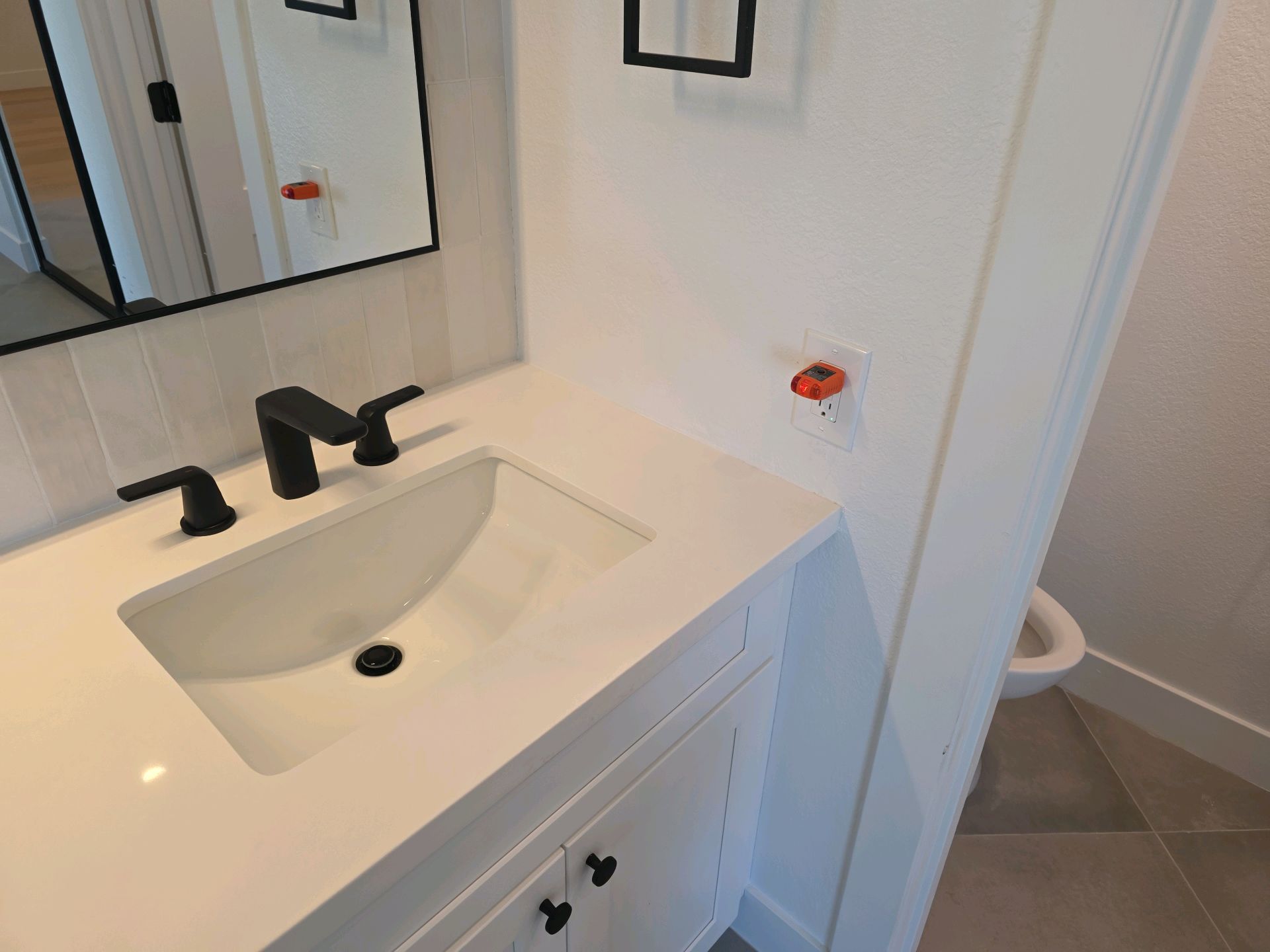Remodeled bathroom vanity with an outlet tester plugged into the GFCI