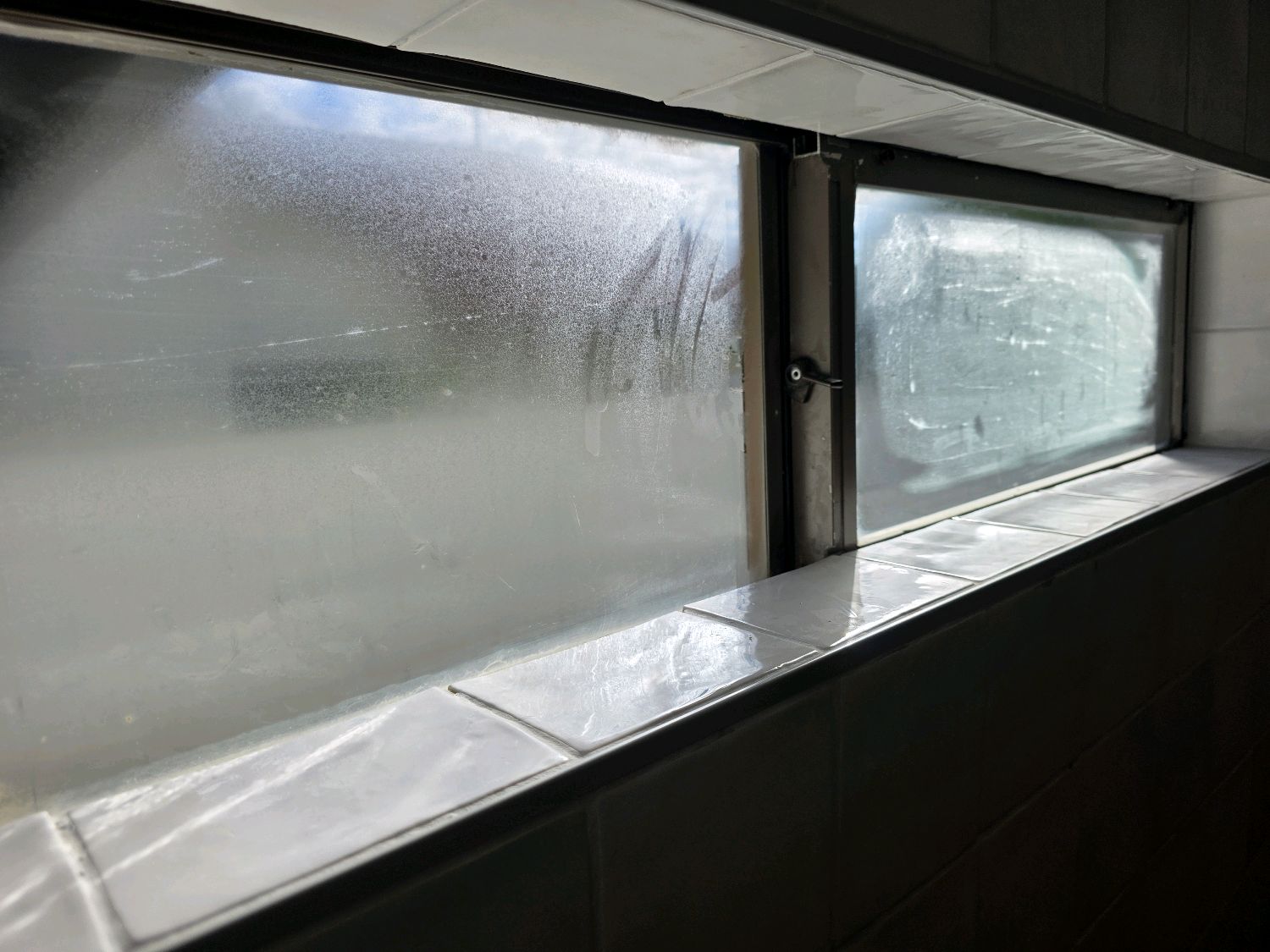 Bathroom wall tile installed over the edge of a window frame